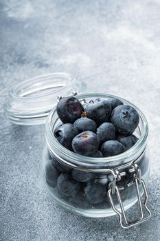 Ripe blueberry in glass jar, on textured background.