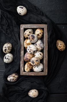 Organic quails eggs, top view, on black wooden background
