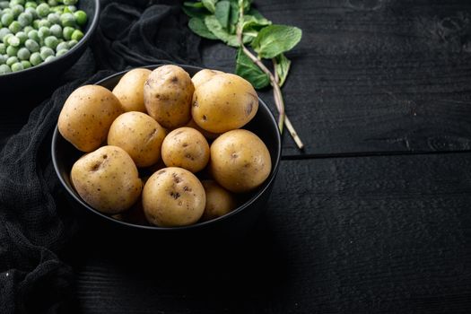 Raw organic baby gold potatoe, on black wooden background with space for text