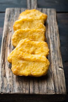 Homemade chicken nuggets fried on dark wooden background.