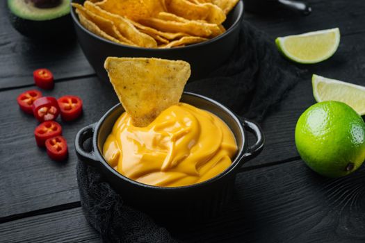 Bowl with cheese sauce set, on black wooden background