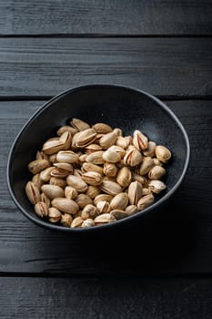 Shelled, unsalted pistachios, on black wooden table