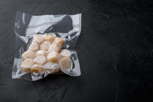 Scallops, in vacuum pack, on black textured background with copy space