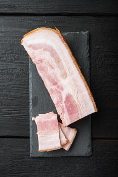 Bacon pancetta cut and sliced on black wooden table, top view.