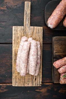Homemade chicken meat sausages, top view, on old dark wooden background.