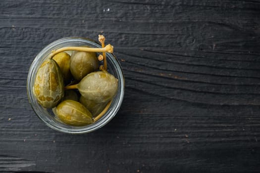 Organic pickled, canned capers, on black wooden background, top view with copy space for text