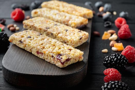 Granola bar with raisins and berry, on black wooden table