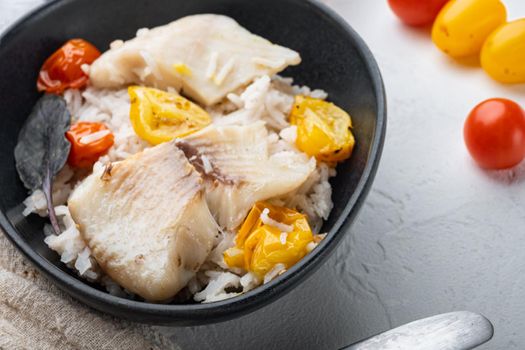Tilapia fish with basmati rice and cherry tomatoes, in bowl, on white background