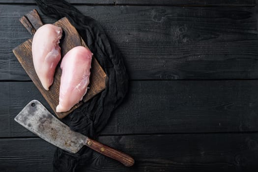 Chicken raw fillets with butcher knife on black wooden table, flat lay with space for text