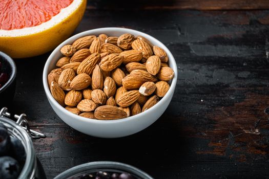 Almonds nuts in bowl on dark wooden background, with copy space.