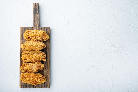 Spicy deep fried breaded chicken wings cuts on white background, top view, with copy space.