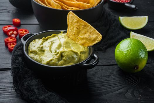 Avocado dip or guacamole in bowl, on black wooden background