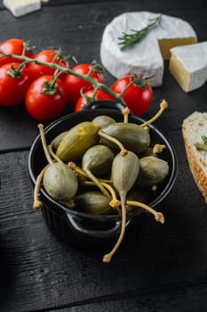 Capers, marinated in oil, on black wooden table
