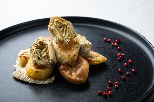 Baked potato, artichoke with fennel al forno, on white textured background