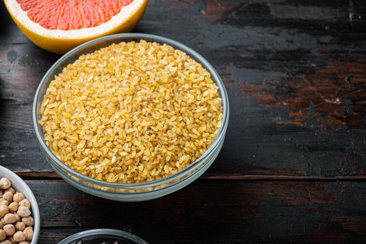 Bulgur grain in bowl on dark wooden background, with space for text.