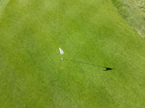 Aerial view of flag mark in hole on golf field. Game, entertainment, sport and leisure concept -