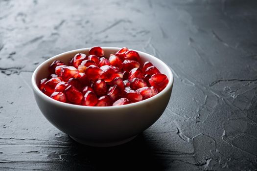 Ripe pomegranate with juicy seeds, on black textured background with space for text