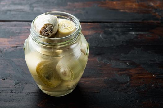 Canned artichokes with olive oil, on old wooden table with space for text