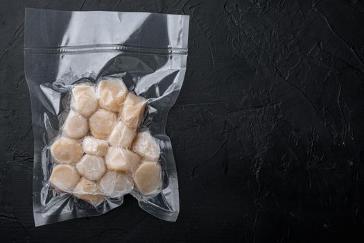 Scallops, in vacuum pack, top view, on black textured background with copy space