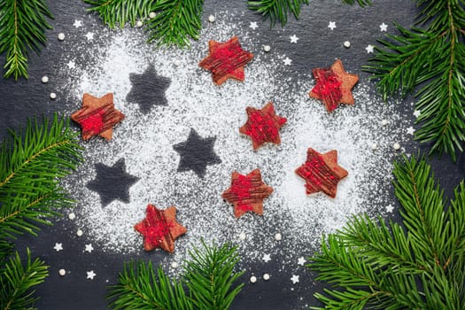 Homemade christmas cookies chocolate stars with raspberry crunches with sugar powder on slate table with pine branches