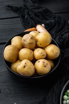 Fresh unpeeled, baby potatoes, on black wooden background