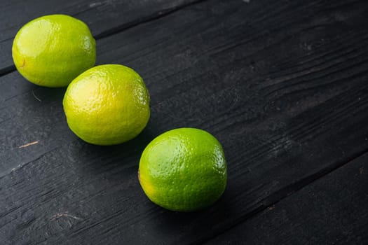 Whole green lime set, on black wooden background with copy space for text