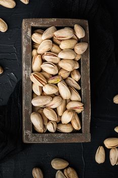 Shelled, unsalted pistachios, on black textured background, flat lay