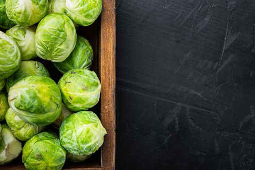 Raw brussels sprouts, on black textured background, top view with space for text