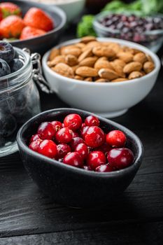 Cranberry, ripe red berry in bowl, on black wooden background.