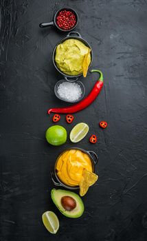 Green guacamole and yellow cheese dip sauce for traditional, Mexican tacos, on black background, top view or flat lay with copy space for text