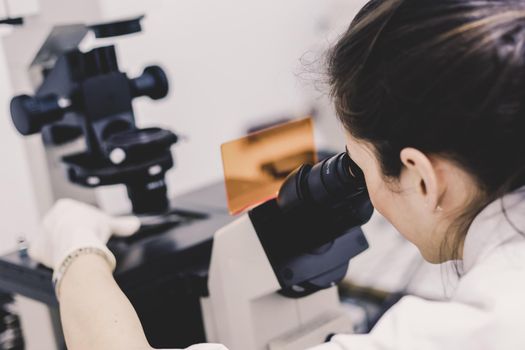 Life science female researcher microscoping in scientific genetic laboratory. Healthcare and biotechnology.