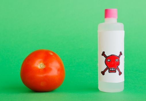 a tomato with a bottle that contains pesticide with the symbol of death