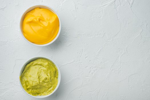Green guacamole and yellow cheese dip sauce for traditional, Mexican tacos, on white background, top view or flat lay with copy space for text