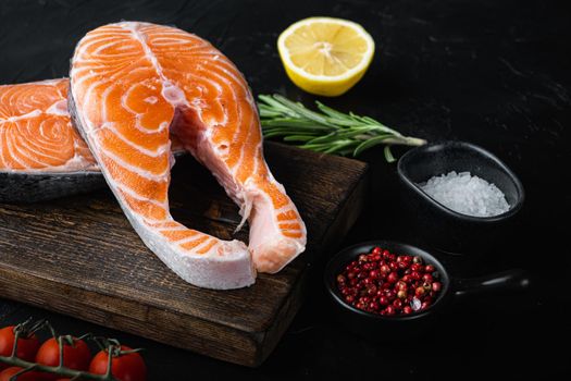 Slice of red fish trout with herbs, over black background.