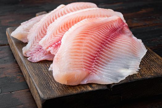 Raw white fish fillet cuts, on dark wooden background
