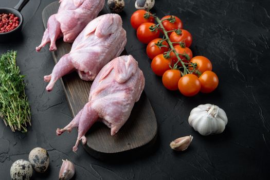 Fresh raw meat quails with herb, on black textured background