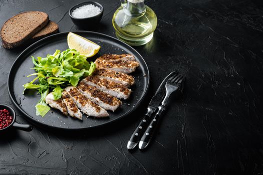 Crumbed, chicken breast fillet grilled, on black background with space for text