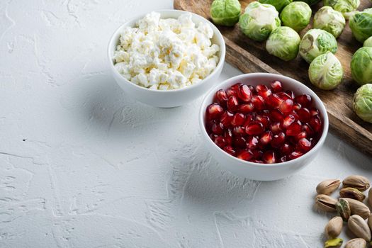 Ripe pomegranate with juicy seeds, on white textured background with space for text