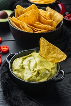 Guacamole traditional mexican spicy avocado dip in bowl, on black wooden background