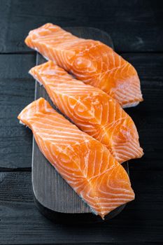 Raw salmon fillet, on black wooden table