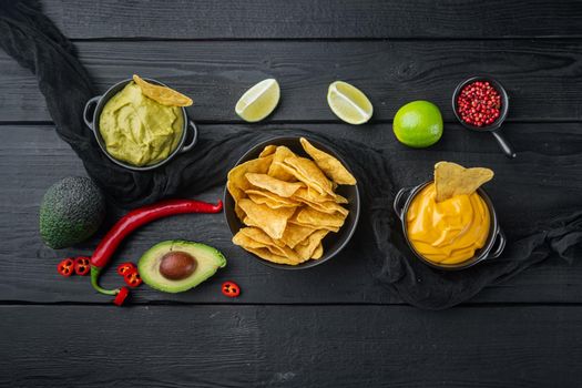Mexican nachos with sauce set, on black wooden background, top view or flat lay with copy space for text