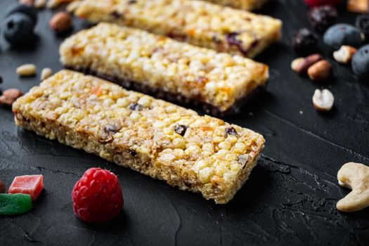 Homemade granola bars with mixed nuts, seeds and berries, on black background