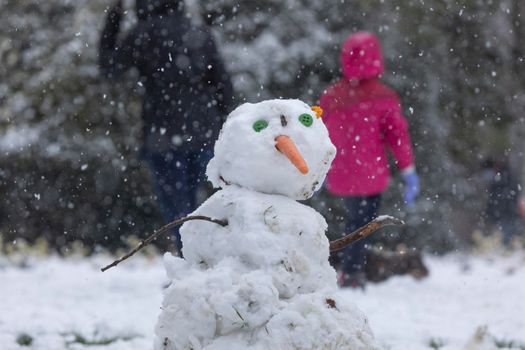 Madrid, Spain - January 08, 2021: Children playing with snow and making snowmen, in the Buen Retiro park in Madrid, in the middle of a snowy day, due to a wave of polar cold.