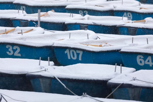 Madrid, Spain - January 08, 2021: Boats covered with snow and moored in the Estanque Grande del Retiro, Madrid, in the middle of a snowy day, due to a wave of polar cold.