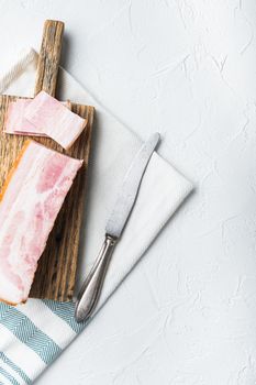 Bacon pancetta cut and sliced on white background, top view with space for text.