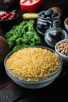 Bulgur grain in bowl on dark wooden background.