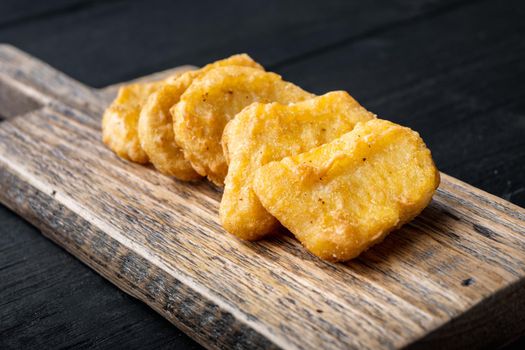 Chicken breast nuggets fried on black wooden background.