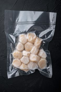 Frozen meat scallops in vacuum package, flat lay, on black textured background
