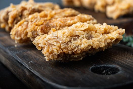 Breaded chicken wings cuts on dark wooden background, with space for text.