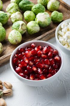 Ripe pomegranate with juicy seeds, on white textured background